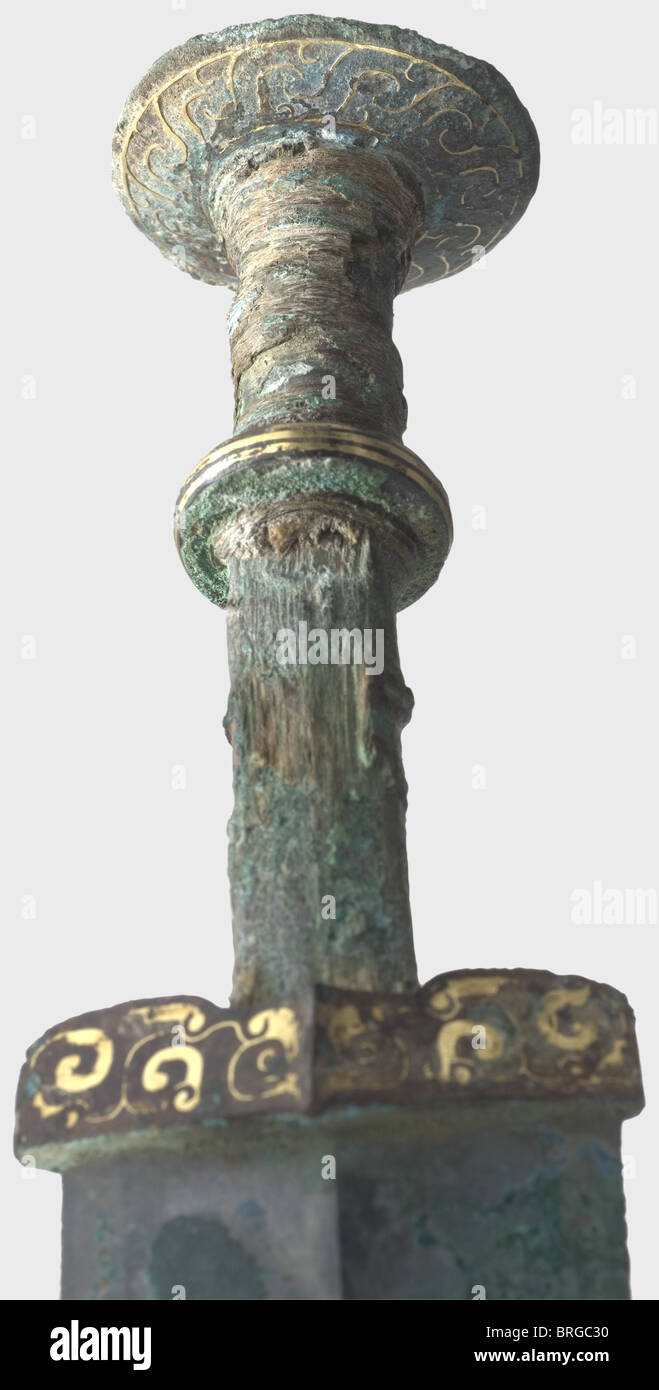 A Chinese bronze sword with a gold-inlaid grip,Warring States period ,5th/4th century B.C. Double-edged,heavily ridged white bronze blade with some heavy green encrustations,as found,and bluish cracks in places. Bronze quillons,disk hilt,and disk pommel have lavish,completely preserved gold inlays. Heavy,greenish patina,the gold threads encrusted in places. Grip has remnants of the wooden grip scales and fabric wrapping. Length 56 cm. Remarkably well-preserved bronze sword of extremely high quality manufacture. A similar example may be found in the ca,Additional-Rights-Clearences-Not Available Stock Photo