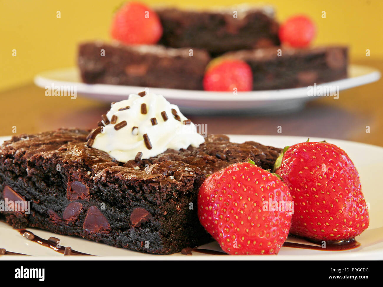 a single fudge brownie with whipped topping in front of a stack behind