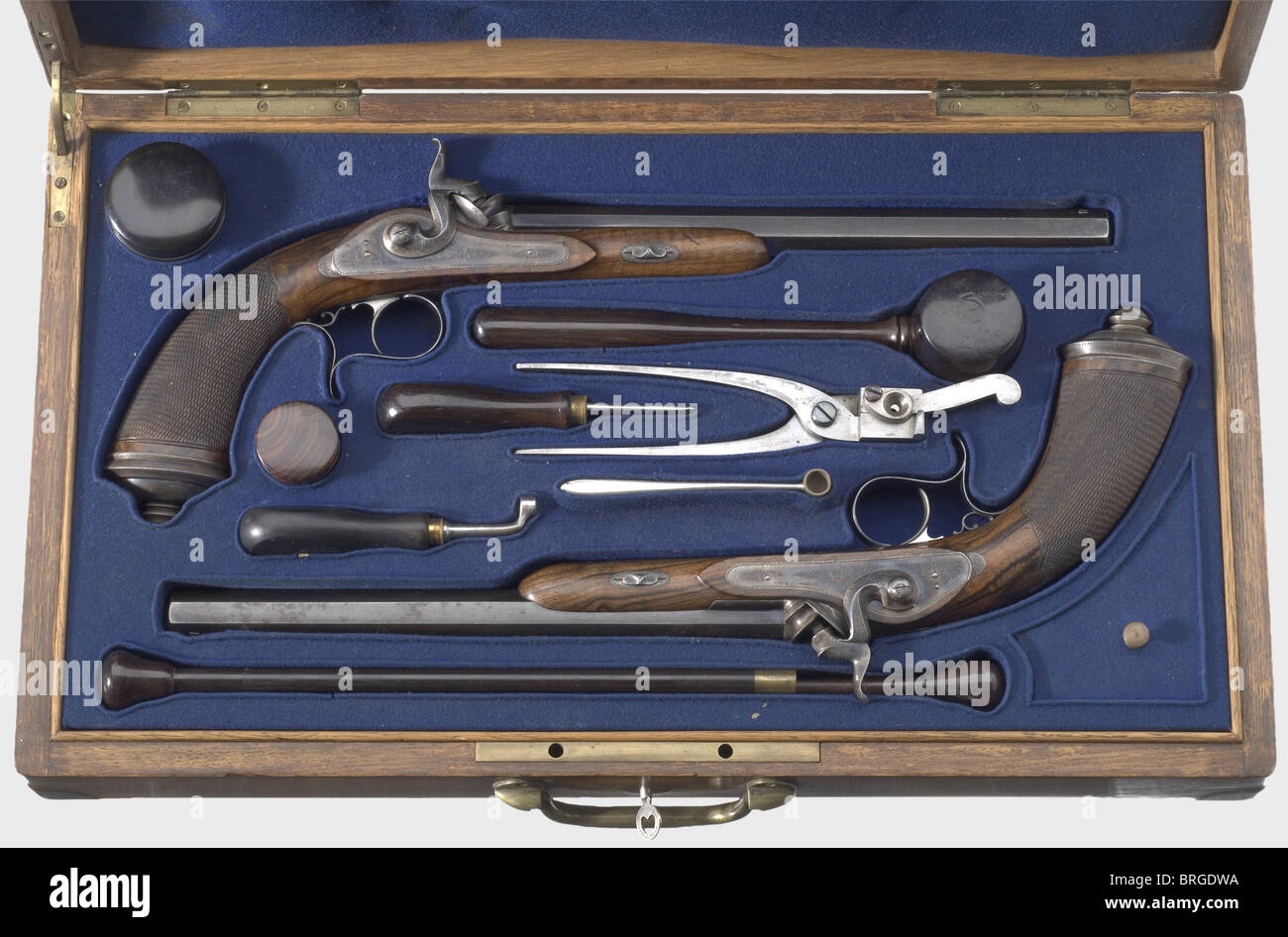 A cased pair of percussion pistols,N.Guyot,Paris,circa 1850.Octagonal blued barrels with patent breechblocks and narrow groove rifling in 11.5 mm calibre.The tops of the barrels are finely engraved with "Guyot Arg.12 Rue de Ponthieu,Paris".Colour case hardened locks with fine ornamental engraving.Walnut stocks with checkered butts and colour case hardened iron furniture engraved en suite.Blank gold escutcheons.Length of each 43.5 cm.In a felt-lined wooden case with brass reinforcements on the corners containing a complete set of accessories.The co,Additional-Rights-Clearences-Not Available Stock Photo