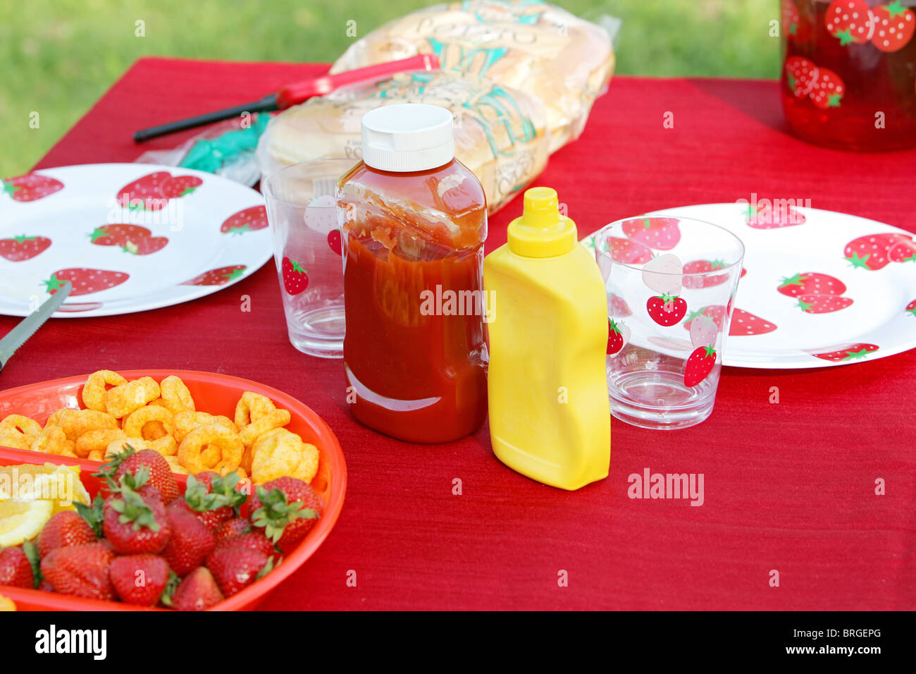 Two bottles of ketchup and mustard on an outdoor picnic table in a park