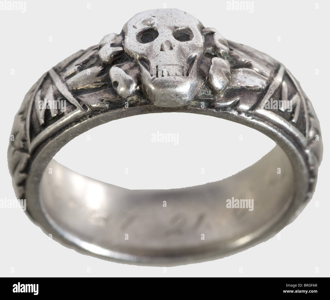 A SS death's-head ring,and a heraldic ring of the Estonian Legion Silver,custom-made issue of the jeweller Gahr in Munich with separately soldered-on death's head. On the inside surface the engraved dedication: 'S.lb. Wonerat 21.6.42. H. Himmler'. Included is a silver ring with a superimposed golden coat of arms of the Estonian Legion. Marks of fineness. Both rings with signs of wear and traces of acid cleaning. Weight 11.5 and 6.5 g respectively.,historic,historical,1930s,20th century,Waffen-SS,armed division of the SS,armed service,armed services,N,Additional-Rights-Clearences-Not Available Stock Photo