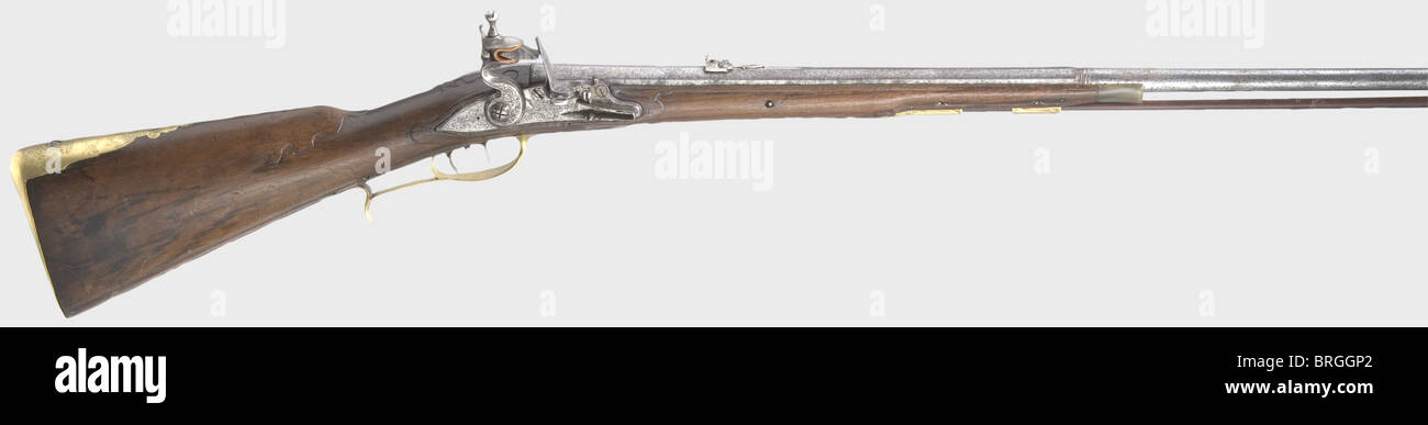 A combined flintlock/air gun,Wentzlau,Neuwied,circa 1740.Octagonal barrel becoming round with a smooth bore in 10.5 mm calibre,engraved brass front sight and replacement iron rear sight,and ornamental engraving(worn)on the breech.Engraved flintlock.The lockplate is signed,'Wentzlau a Neuwied No 61'.There is a screw running through the powder pan to close the vent for use as an air gun.Set trigger.Lightly carved walnut half stock with horn nose cap.Brass furniture with remnants of gilding,finely engraved with ornamental and hunting designs.There,Additional-Rights-Clearences-Not Available Stock Photo