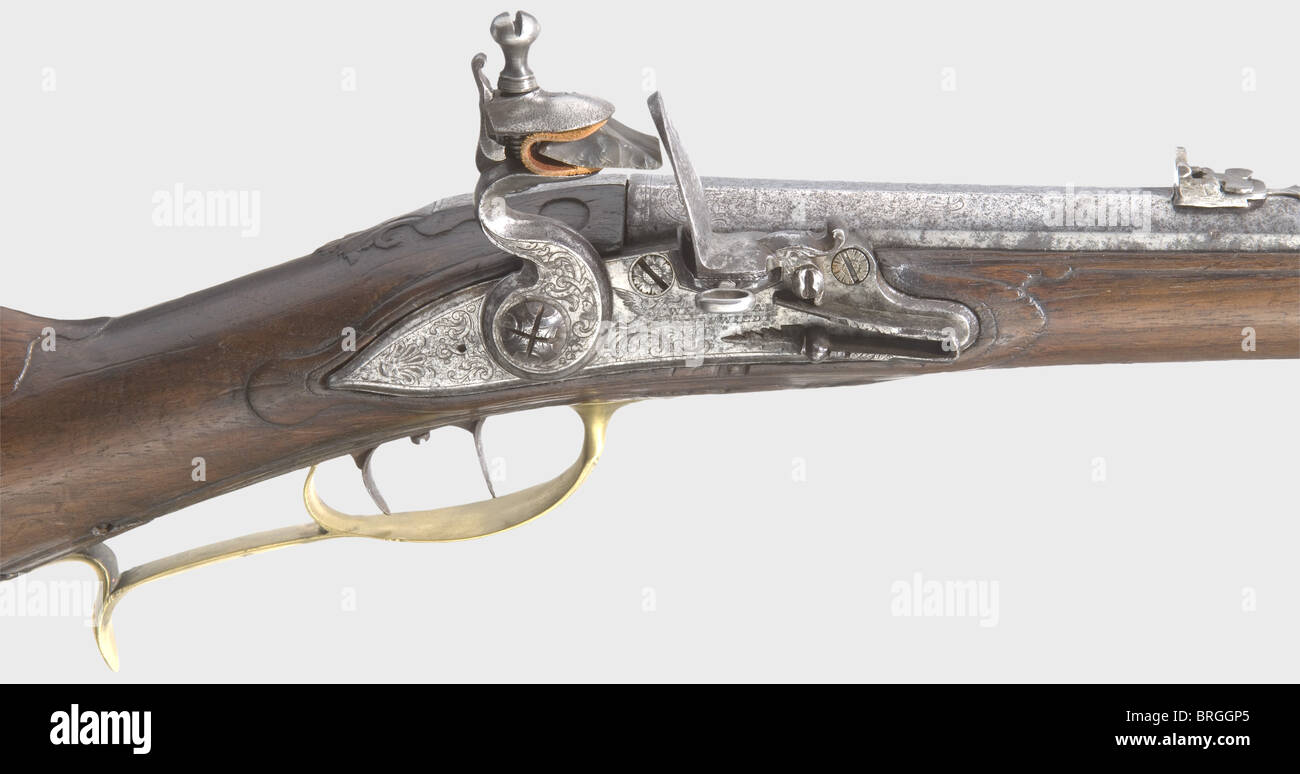 A combined flintlock/air gun,Wentzlau,Neuwied,circa 1740.Octagonal barrel becoming round with a smooth bore in 10.5 mm calibre,engraved brass front sight and replacement iron rear sight,and ornamental engraving(worn)on the breech.Engraved flintlock.The lockplate is signed,'Wentzlau a Neuwied No 61'.There is a screw running through the powder pan to close the vent for use as an air gun.Set trigger.Lightly carved walnut half stock with horn nose cap.Brass furniture with remnants of gilding,finely engraved with ornamental and hunting designs.There,Additional-Rights-Clearences-Not Available Stock Photo