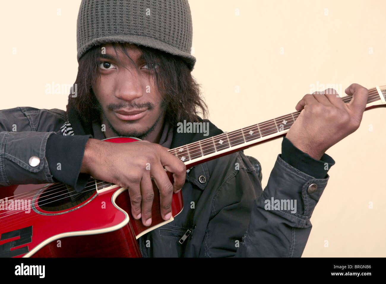 one African American young man holding a red guitar on a yellow ...