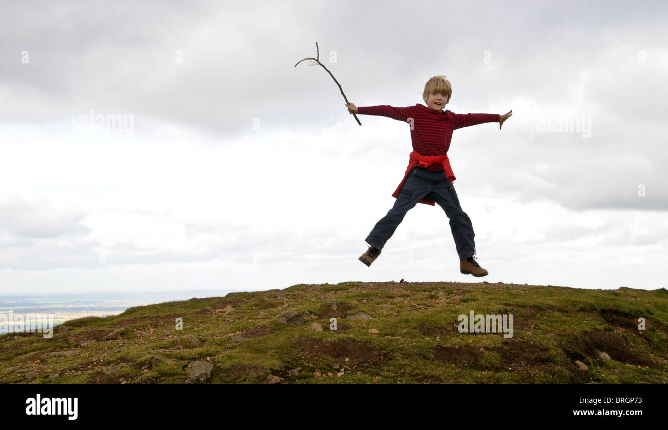 Young boy jumping for joy with his feet off the ground and waving a