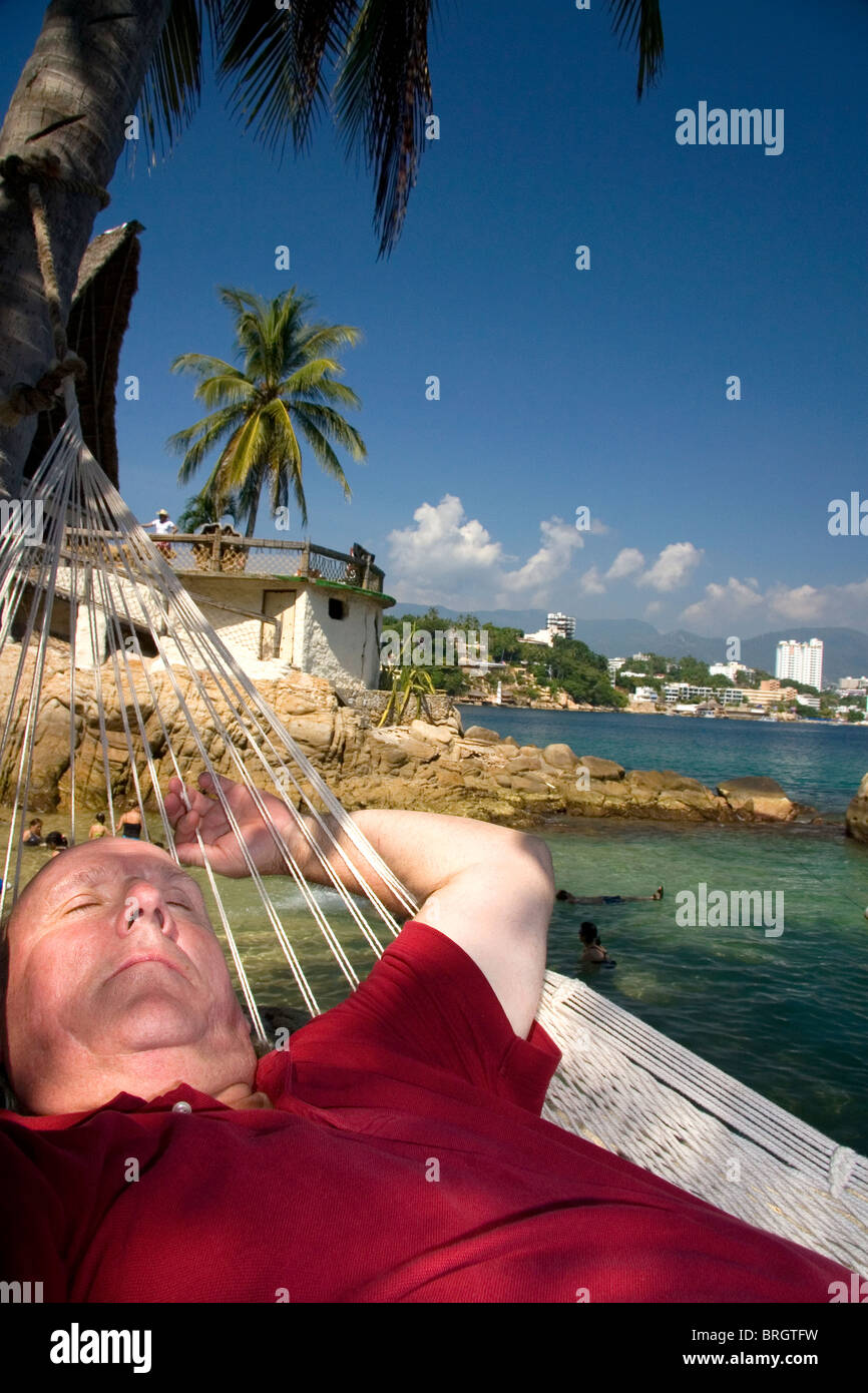 American tourist napping in a hammock on Island Roqueta, Acapulco, Guerrero, Mexico. MR Stock Photo