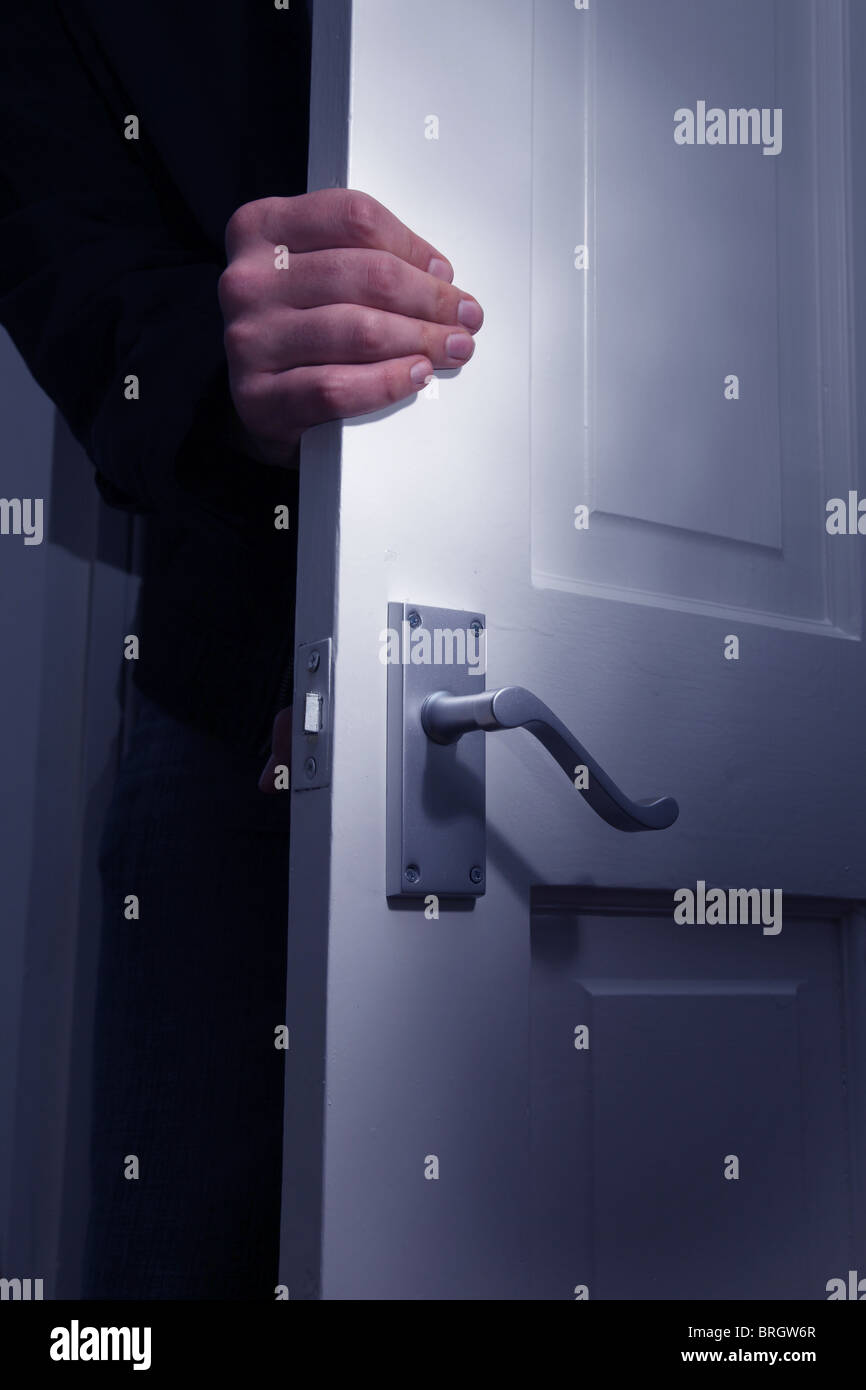 Male hand gripping a door to a dark room as it is opened Stock Photo
