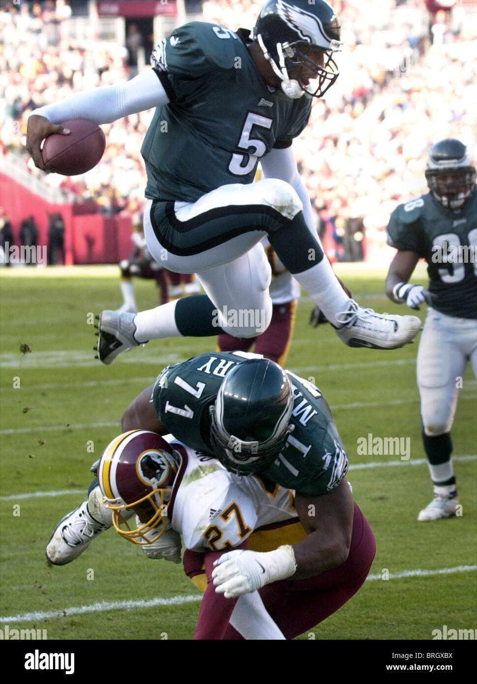 Philadelphia Eagles' Donovan McNabb (5) jumps over Eagles' Jermane Mayberry (71) and Washington Redskins' Mark Carrier (27) ding Stock Photo