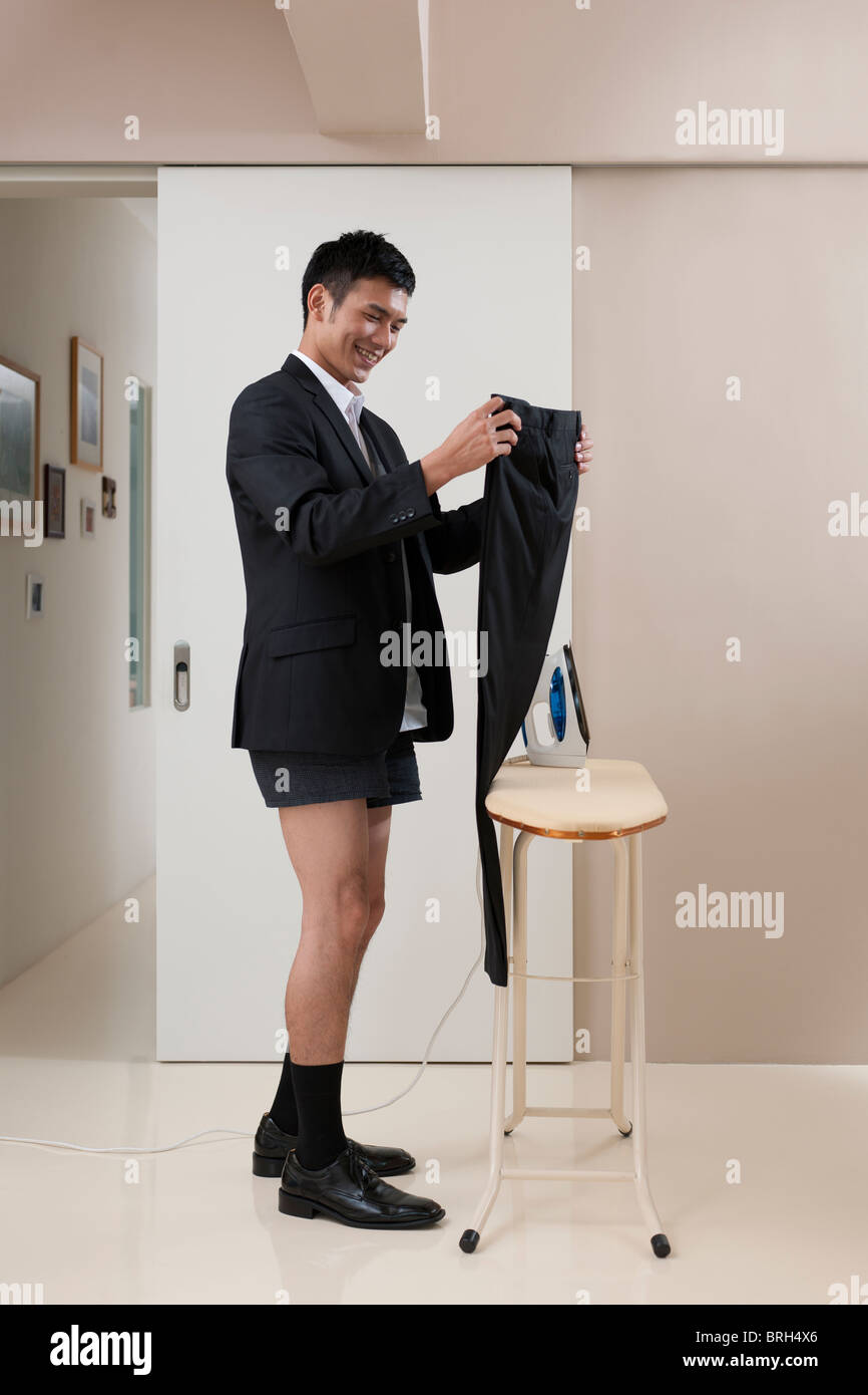 Young man ironing pants Stock Photo Alamy
