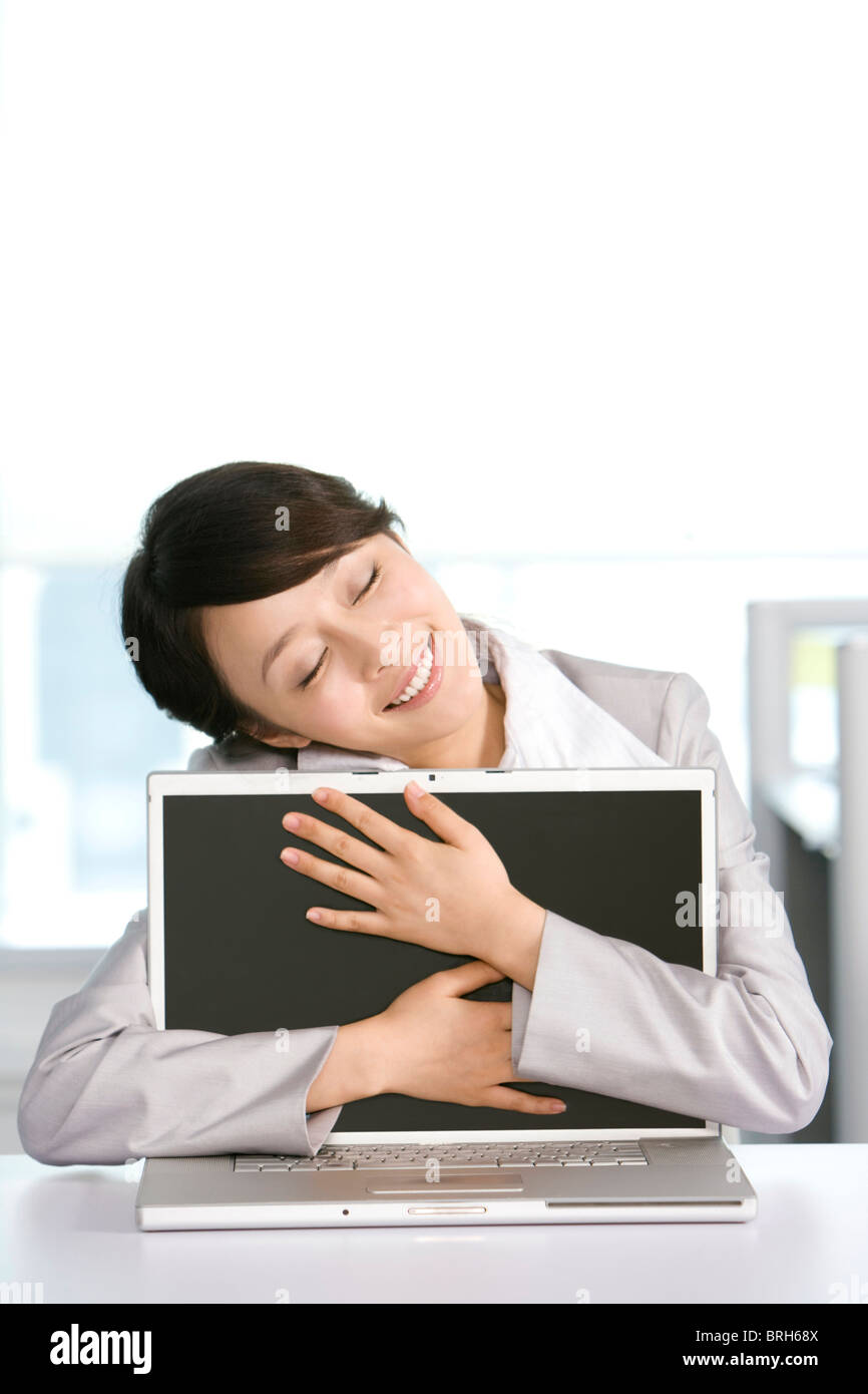 Office worker hugging her computer Stock Photo - Alamy