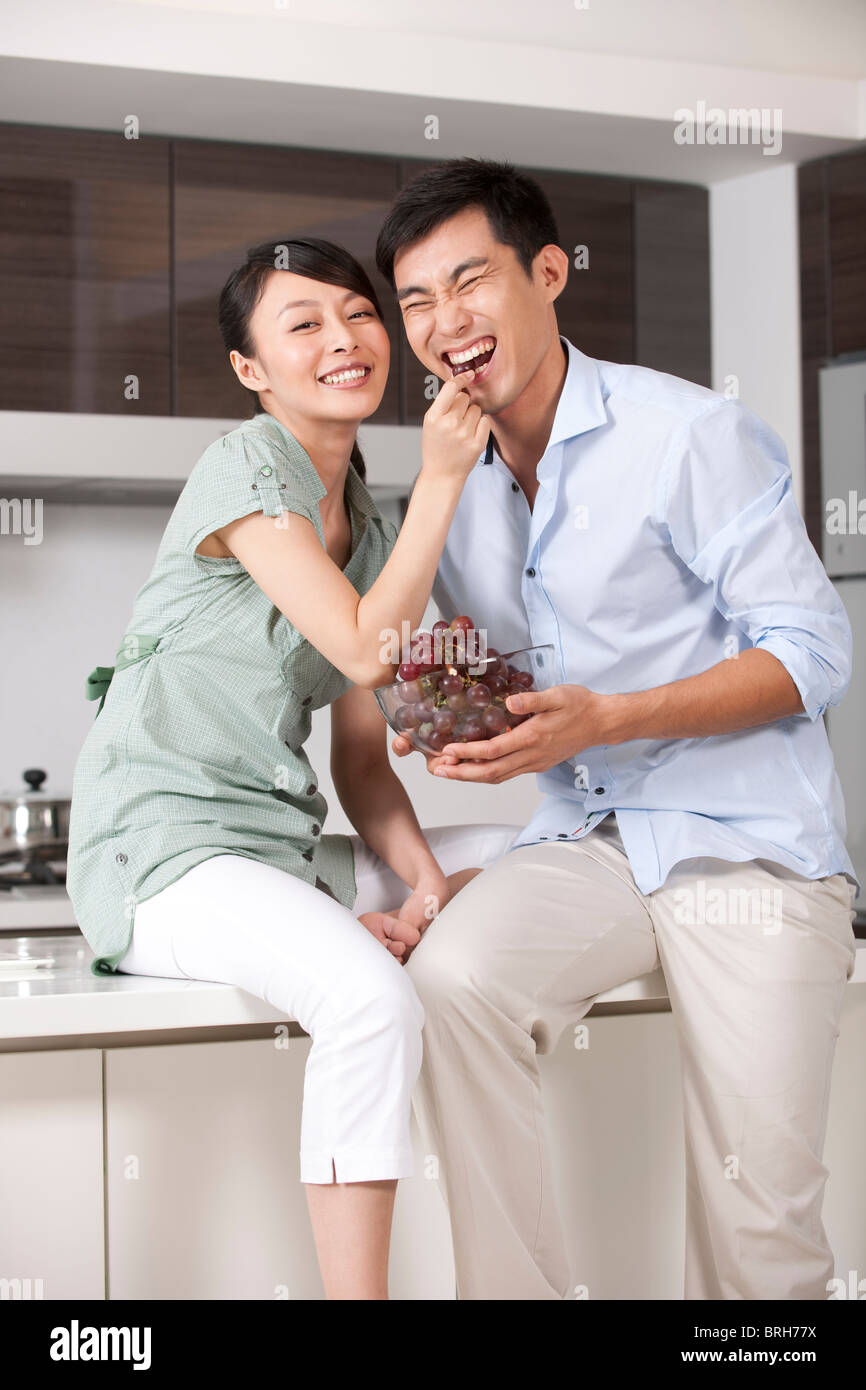 Woman feeding man grapes in the kitchen Stock Photo - Alamy