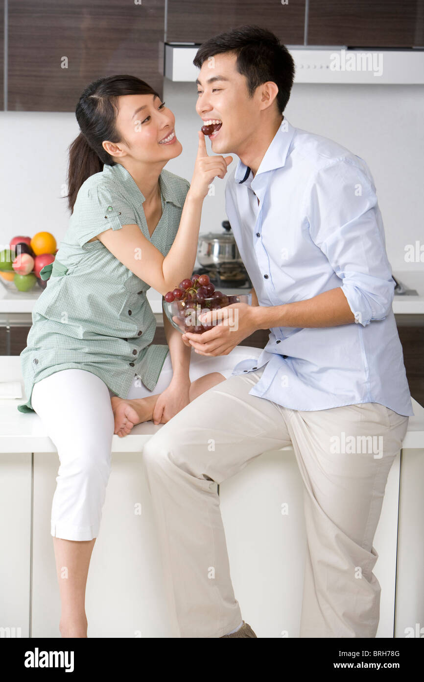 Woman feeding man grapes in the kitchen Stock Photo - Alamy
