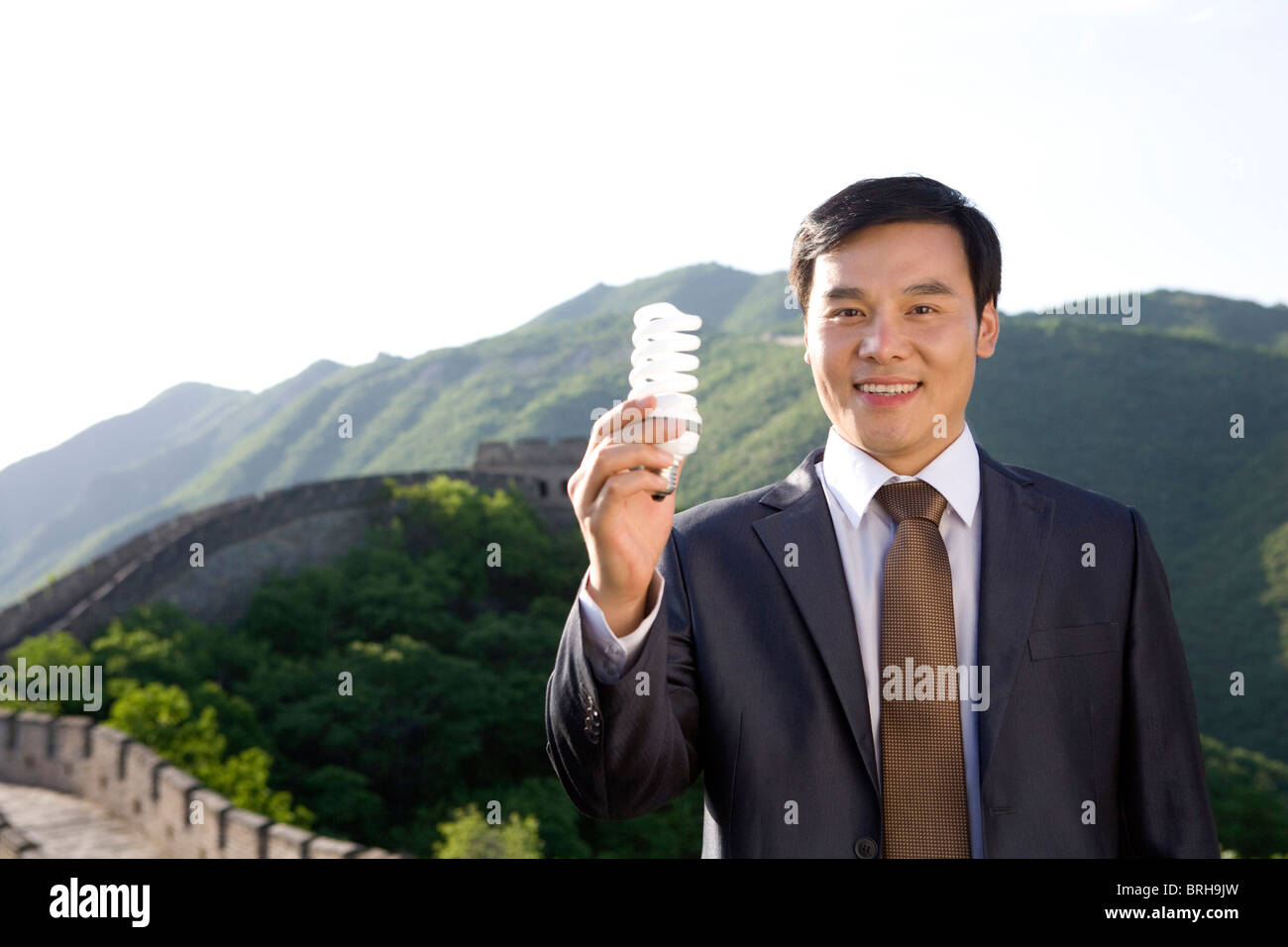 Businessman holding a light bulb while on the Great Wall Stock Photo