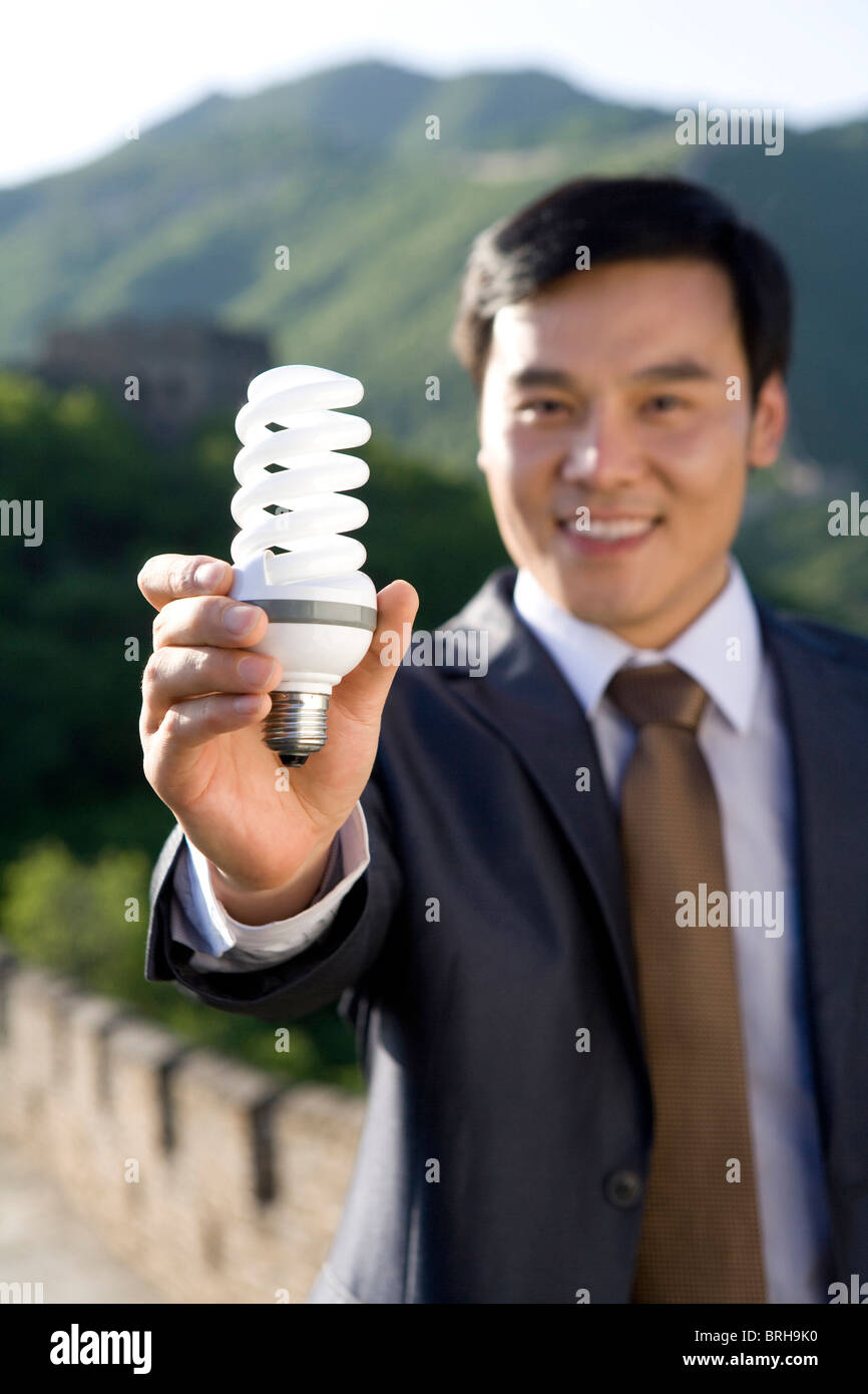 Businessman holding a light bulb while on the Great Wall Stock Photo ...