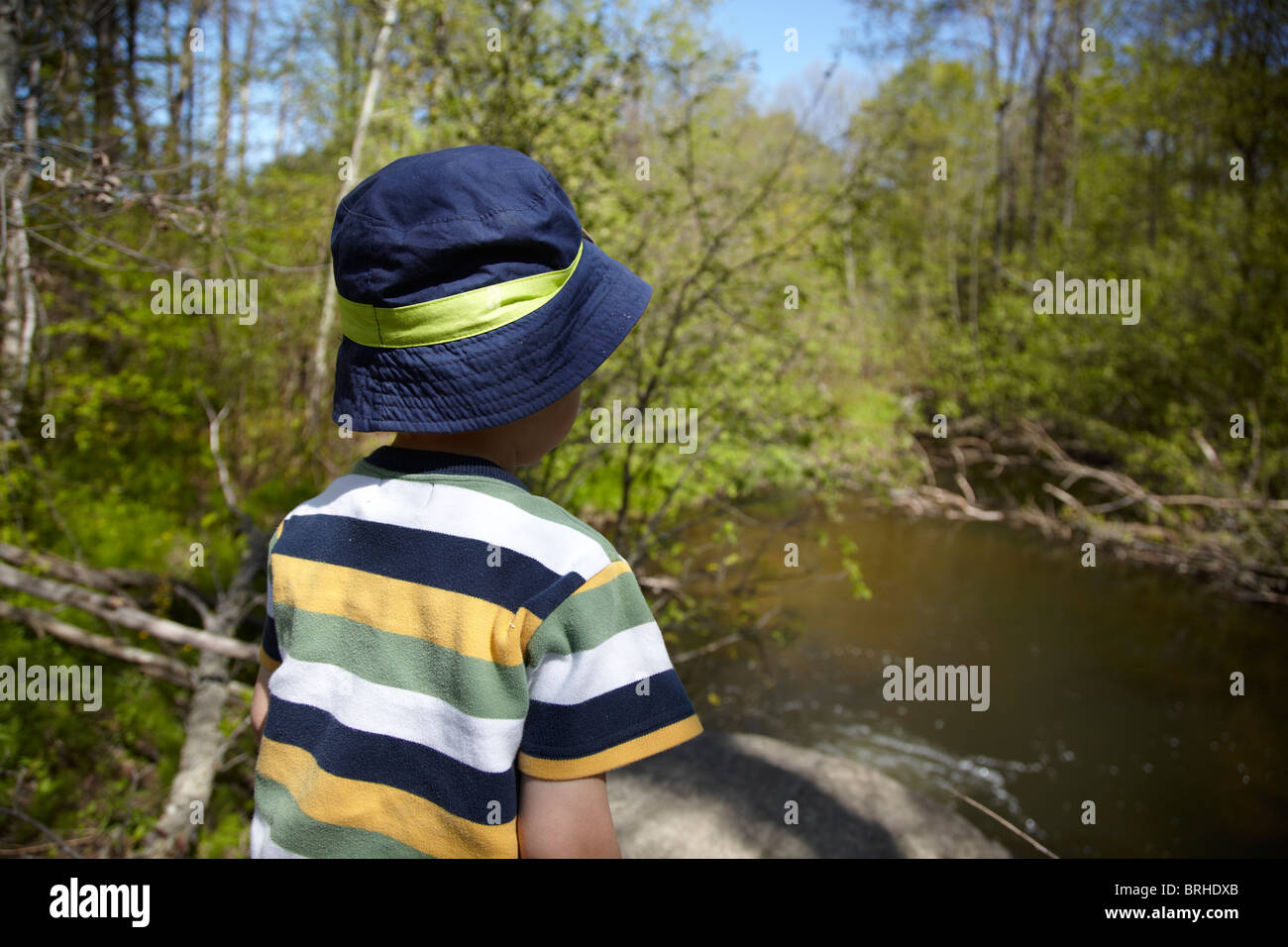 Close-up of Back View of Child wearing Sunhat, standing next to River Stock Photo