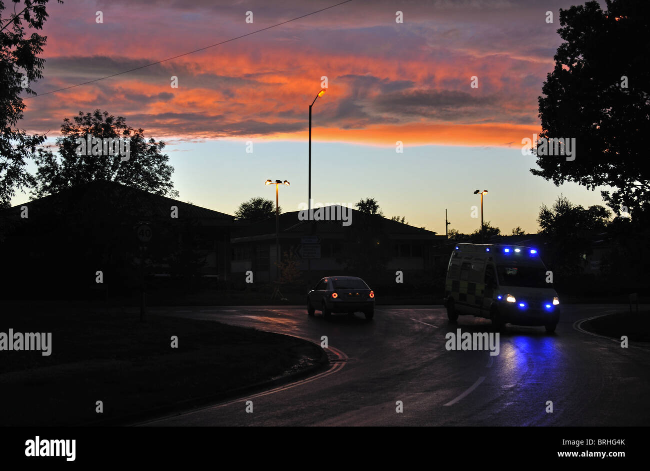 Ambulance on dark road at sunset, UK Stock Photo