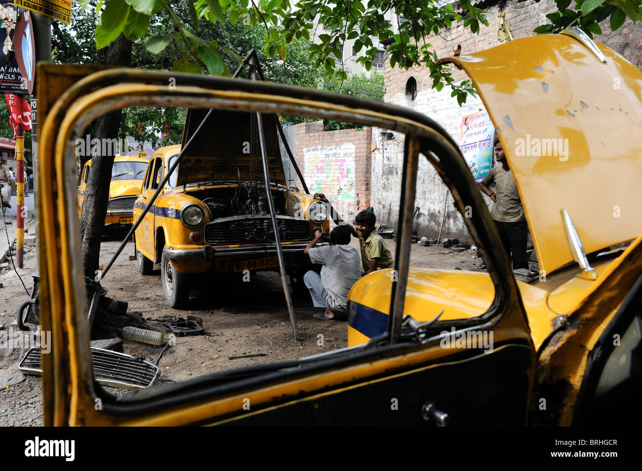 INDIA Calcutta Kolkata , mechanic repair a yellow cab , a HM Ambassador car , which is based on Oxford Morris, in roadside garage Stock Photo