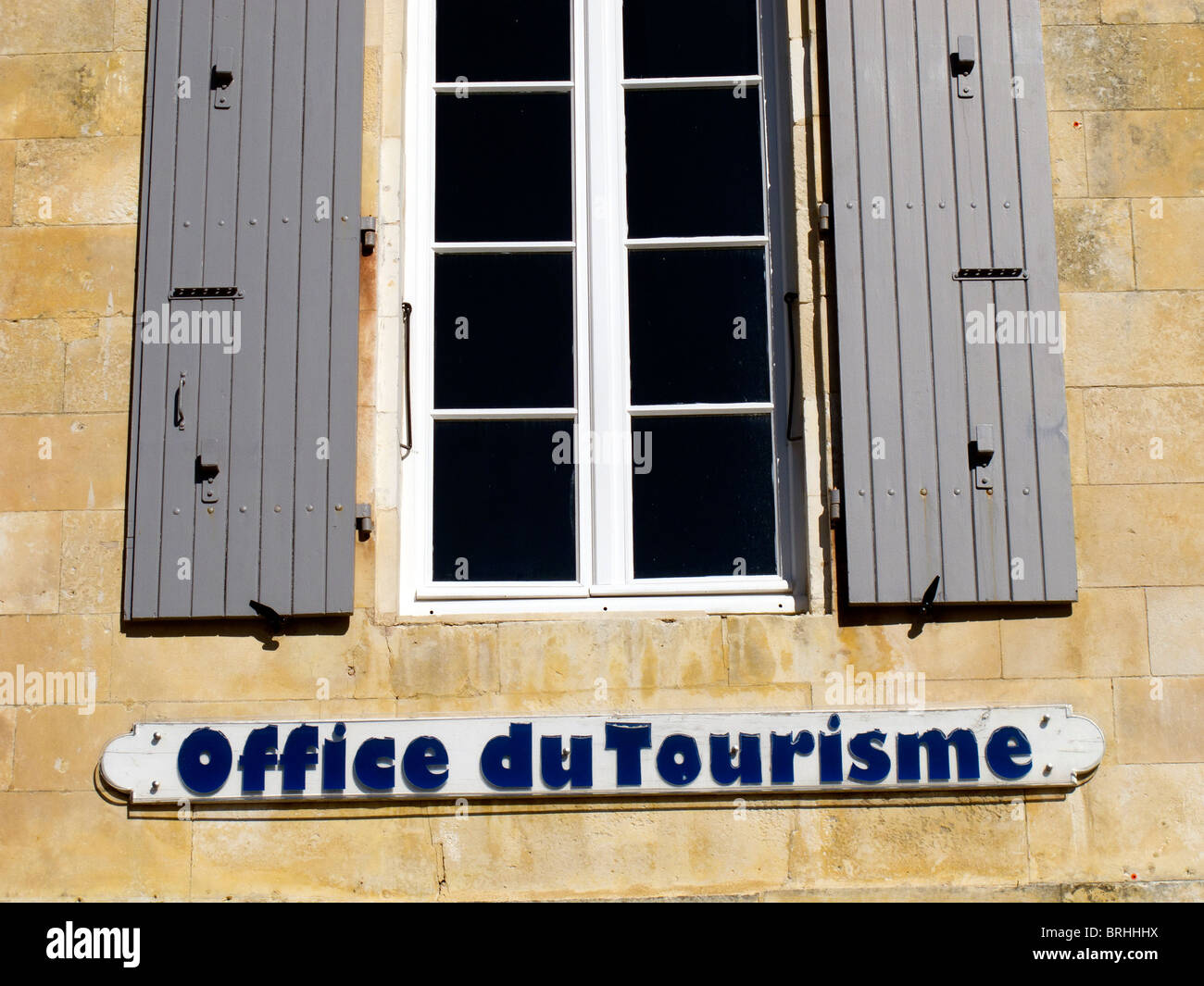 Sign for the Office of Tourism beneath a window with shutters in St Martin de Re on the French island of Ile de Re Stock Photo