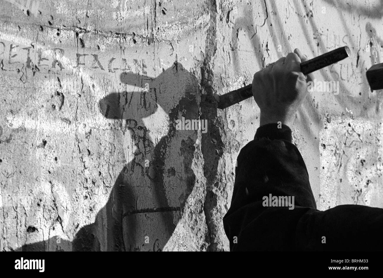 A west Berliner cuts a hole in the Berlin Wall Stock Photo