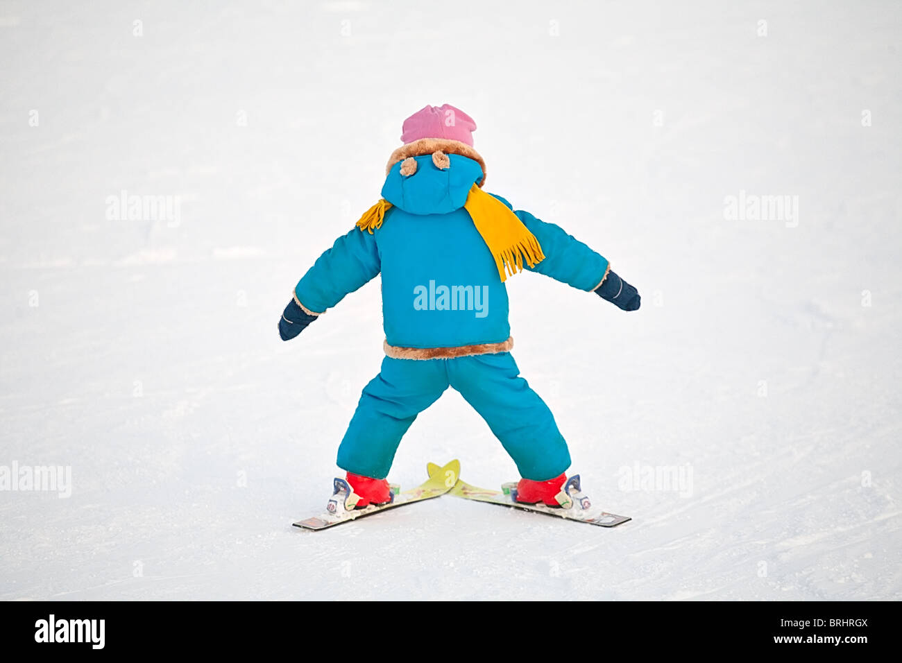 little child doing his first downhill on alpine skis, standing back