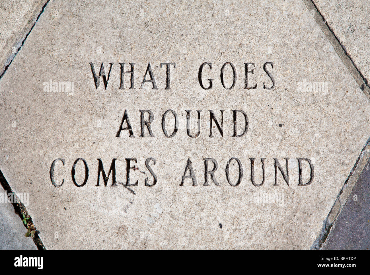 Concrete paver in sidewalk states 'What goes around, comes around' in Ybor City area of Tampa, Florida Stock Photo