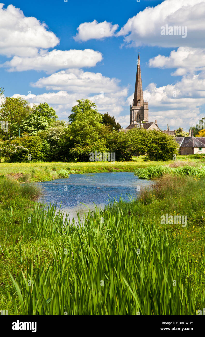 Summer view across meadow and River Windrush to St John the Baptist Church in Cotswold town of Burford, Oxfordshire, England, UK Stock Photo