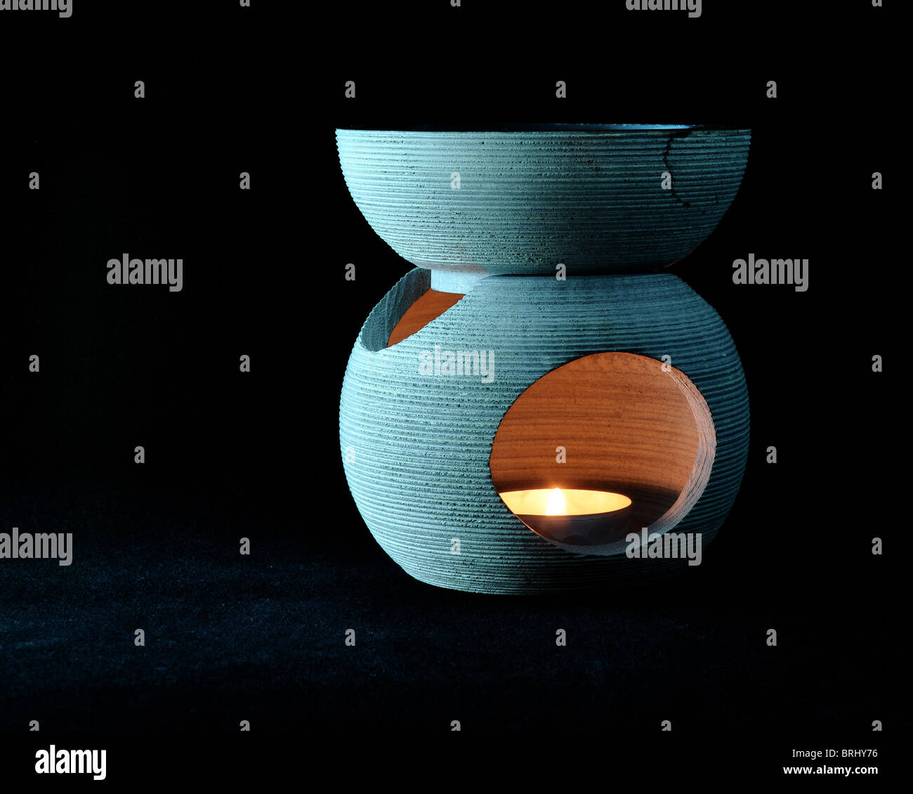 Candle burner against a seamless black background with soft light and