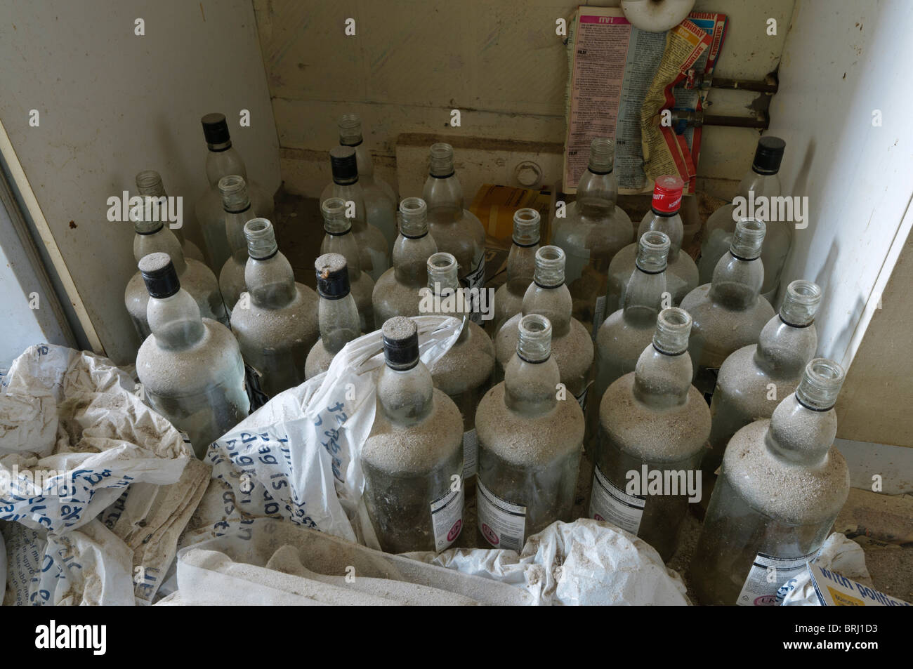 Lots of empty vodka bottles in an abandoned flat, covered in a thick layer of dust Stock Photo