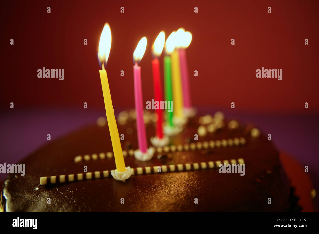 Colorful birthday light candles in a chocolate cake red background