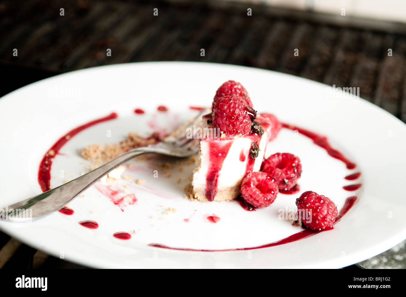 Half eaten raspberry cheesecake on plate with fork Stock Photo