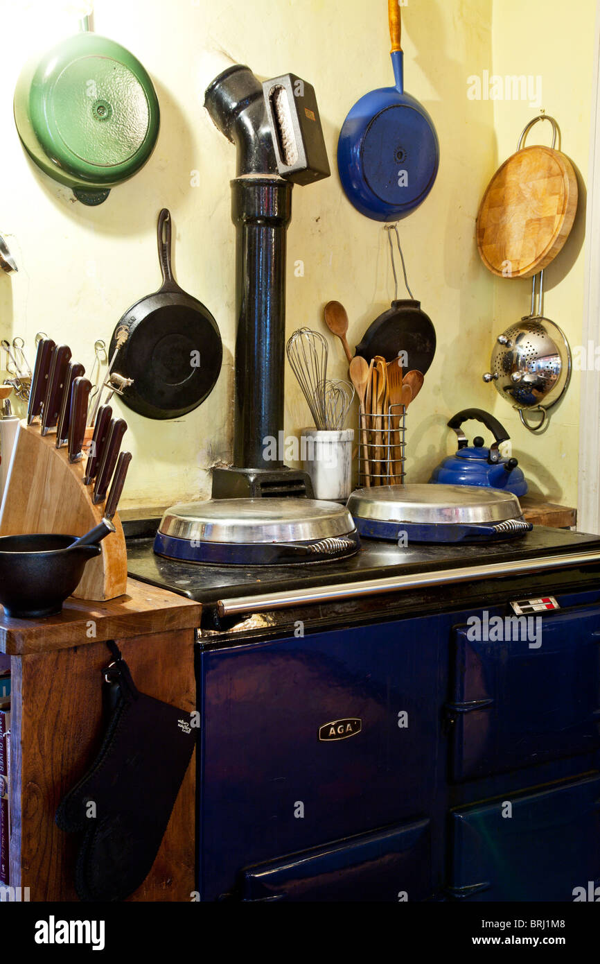 A corner of an English country style kitchen with an Aga or range and pots and pans and cooking utensils Stock Photo