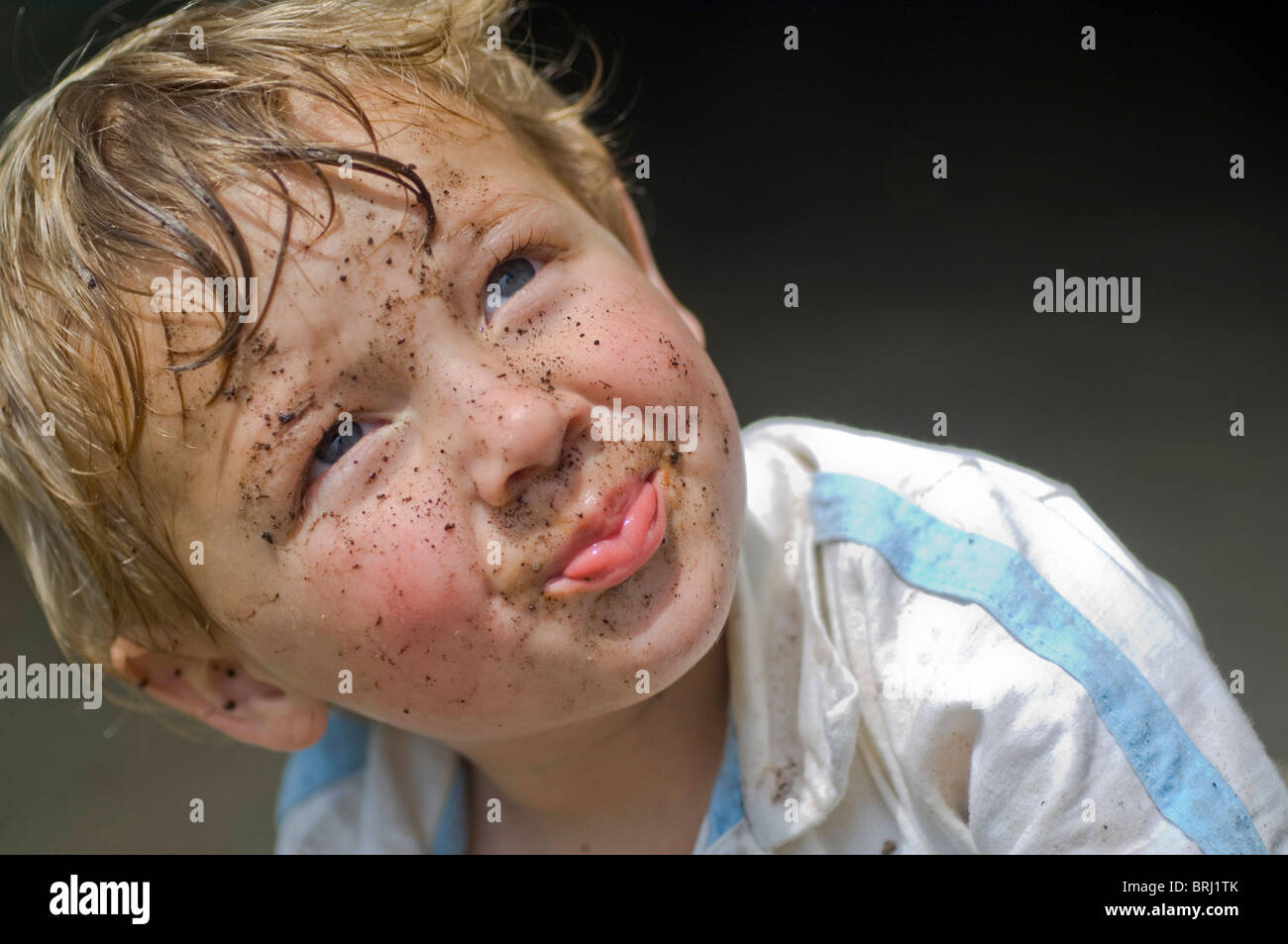 A 3yearold boy looks up with a mud covered face Stock Photo Alamy