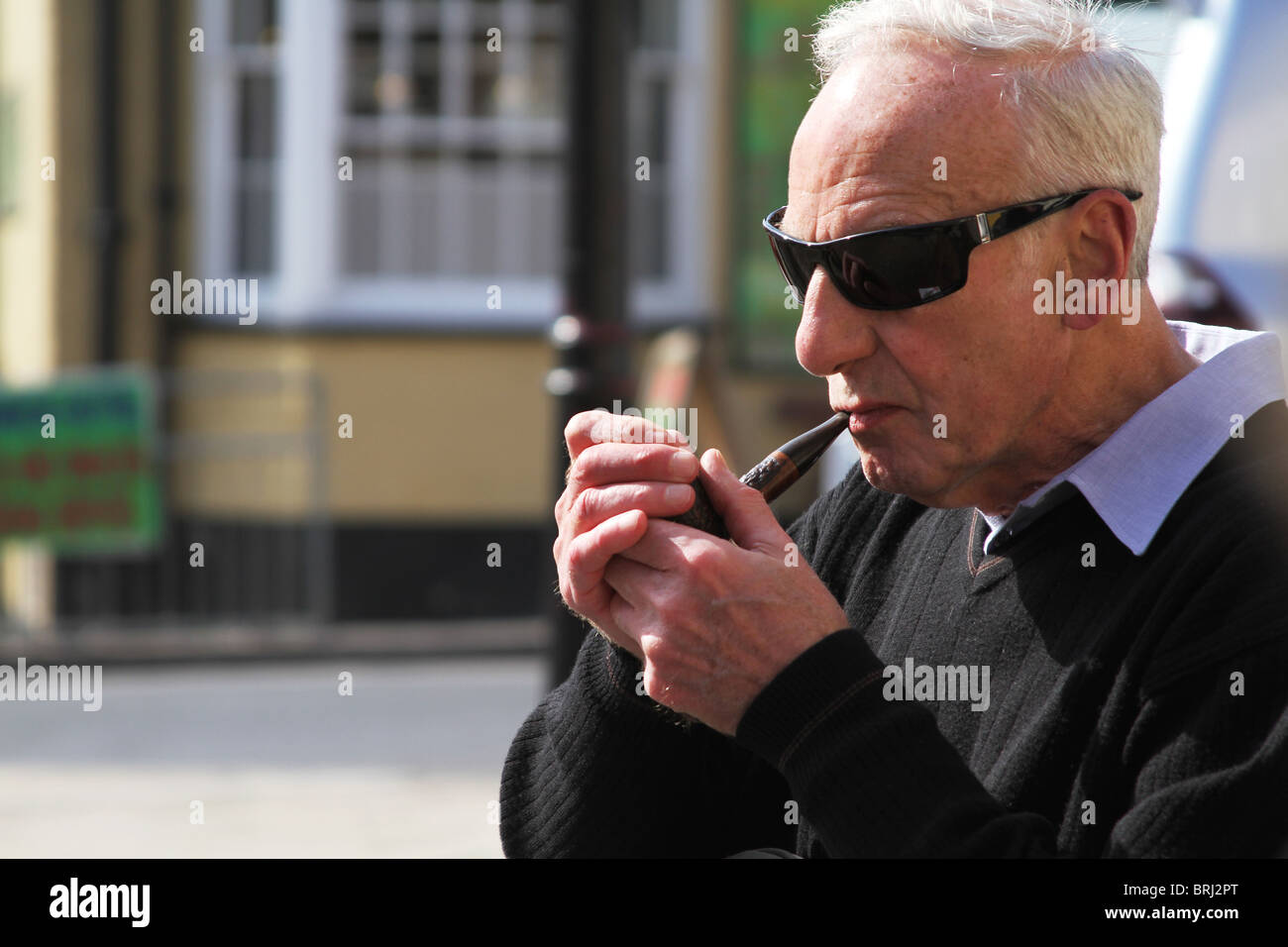 Man lighting a pipe in the street. Stock Photo