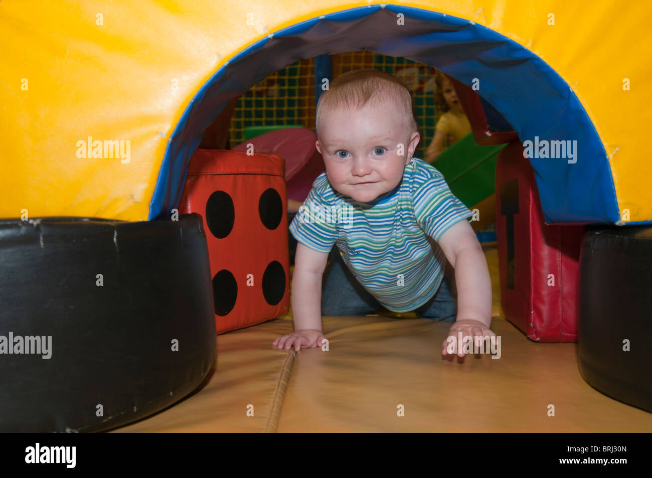 1 year old baby crawling through a play tunnel Stock Photo