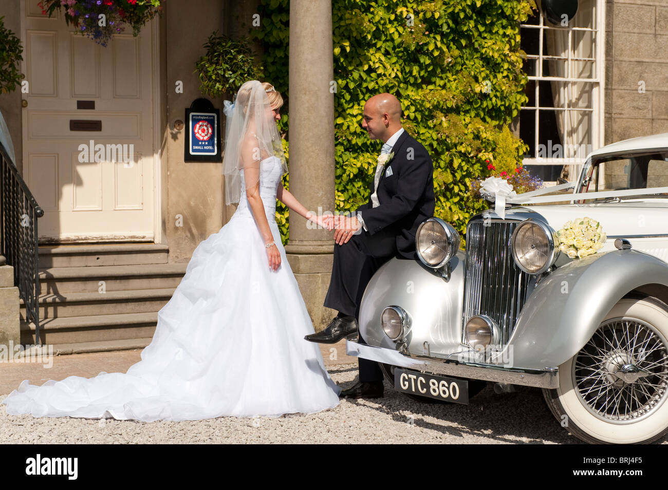 A stunning looking bride and groom next to a vintage wedding car Stock ...
