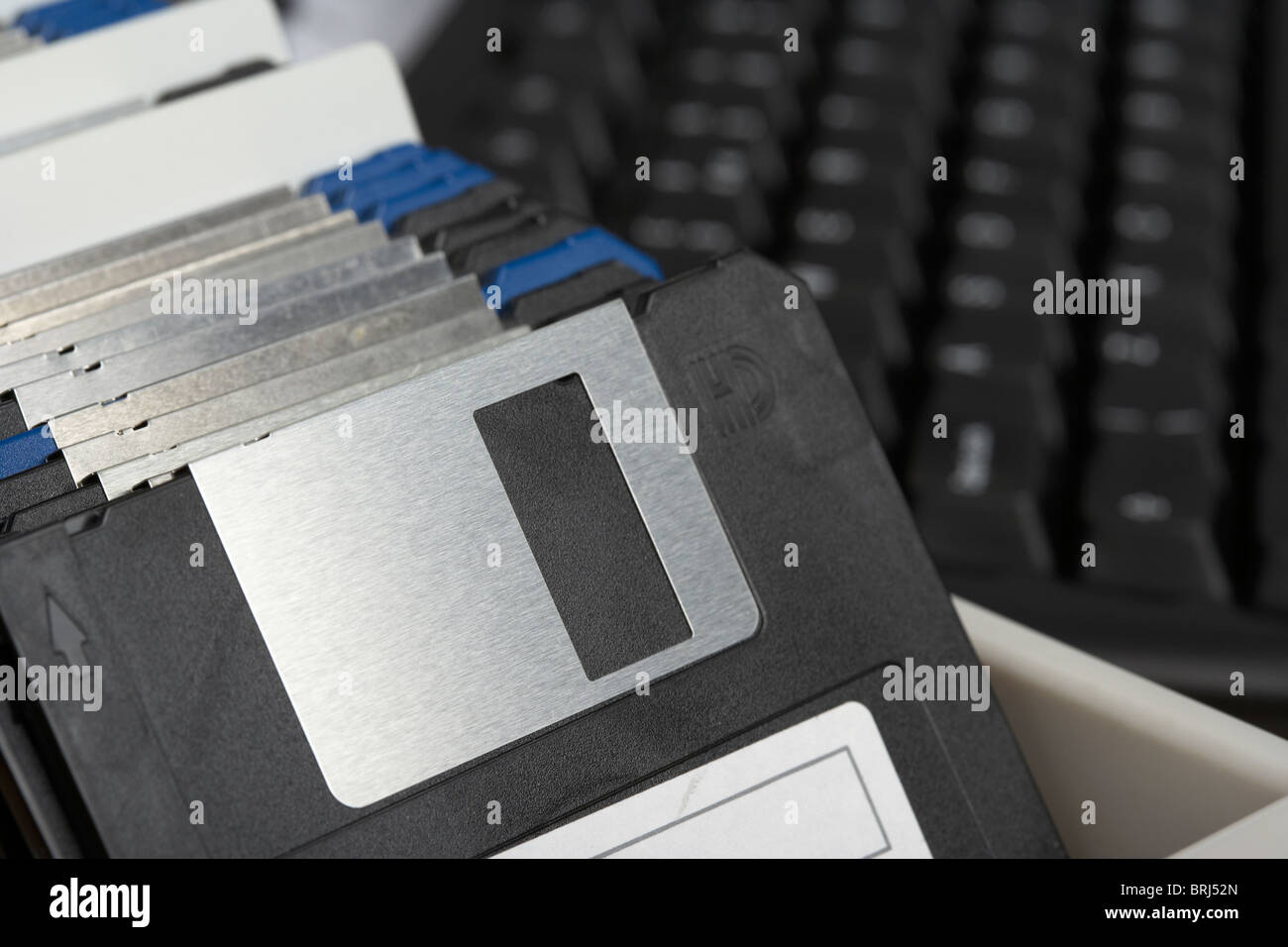 box of old floppy storage disks in front of a computer keyboard Stock Photo