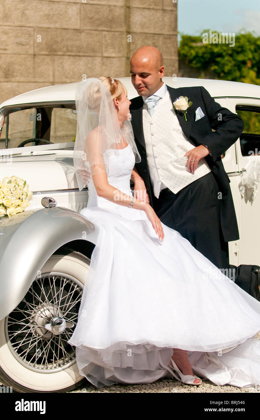 A stunning looking bride and groom next to a vintage wedding car Stock ...