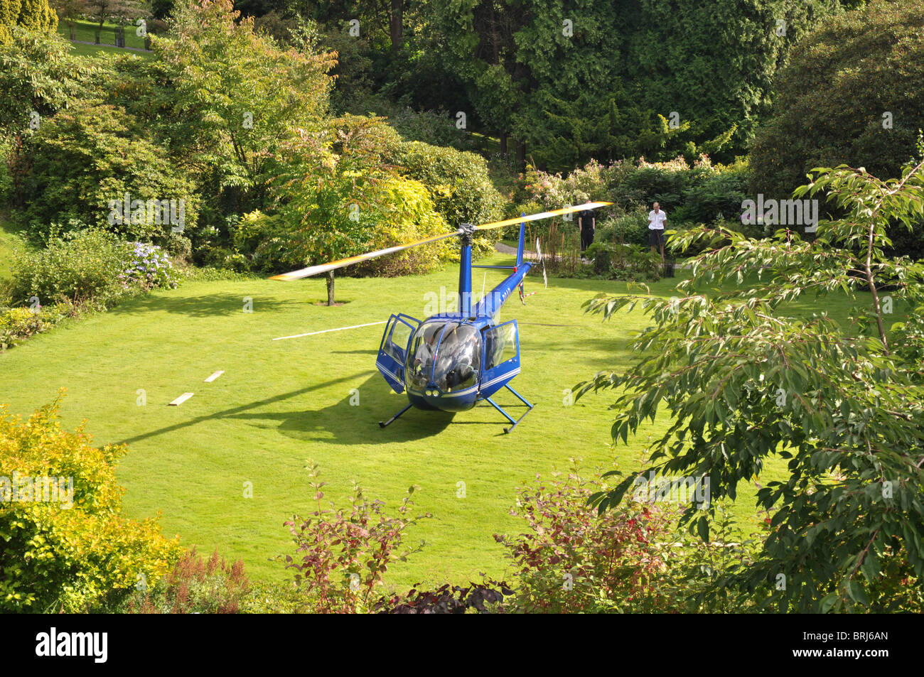 HELICOPTER LANDING IN GARDEN OF HOTEL BETWEEN THE TREES NEAR LAKE ...