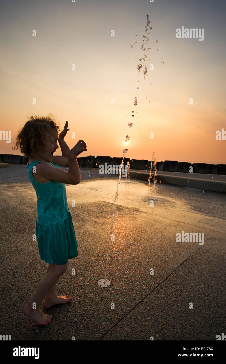 Young girl playing with water jets on Morecambe West Promenade at sunset Stock Photo