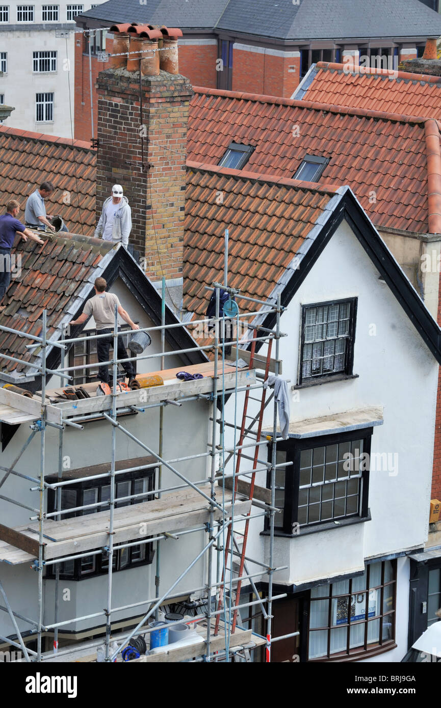 Builders replacing ridge tiles on roof refurbishment, UK Stock Photo