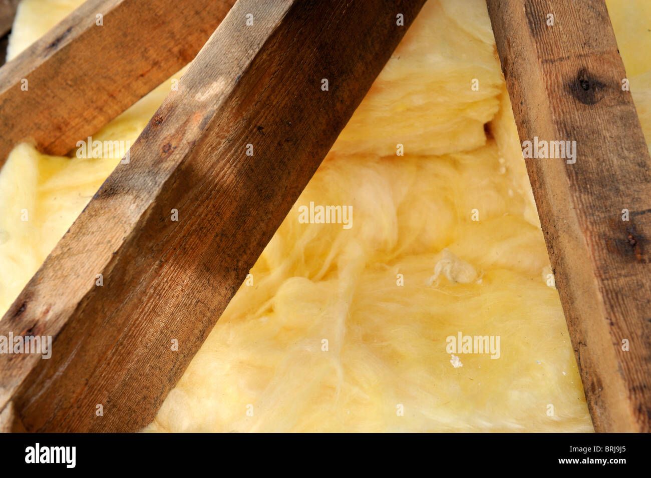 Timber hip roof trusses and fibreglass insulation seen from outside during refurbishment Stock Photo