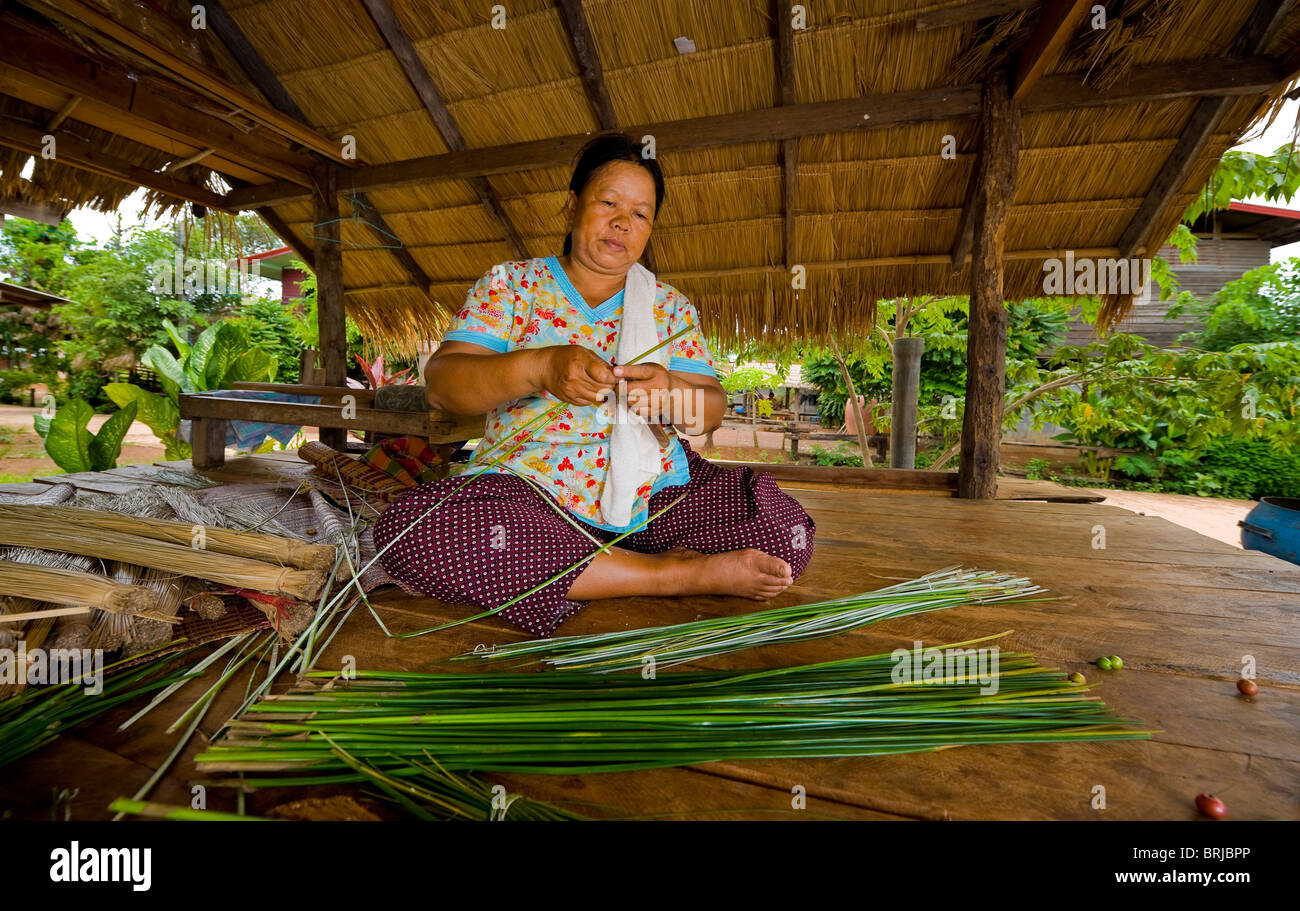 an asian woman making straw mats by hand Stock Photo