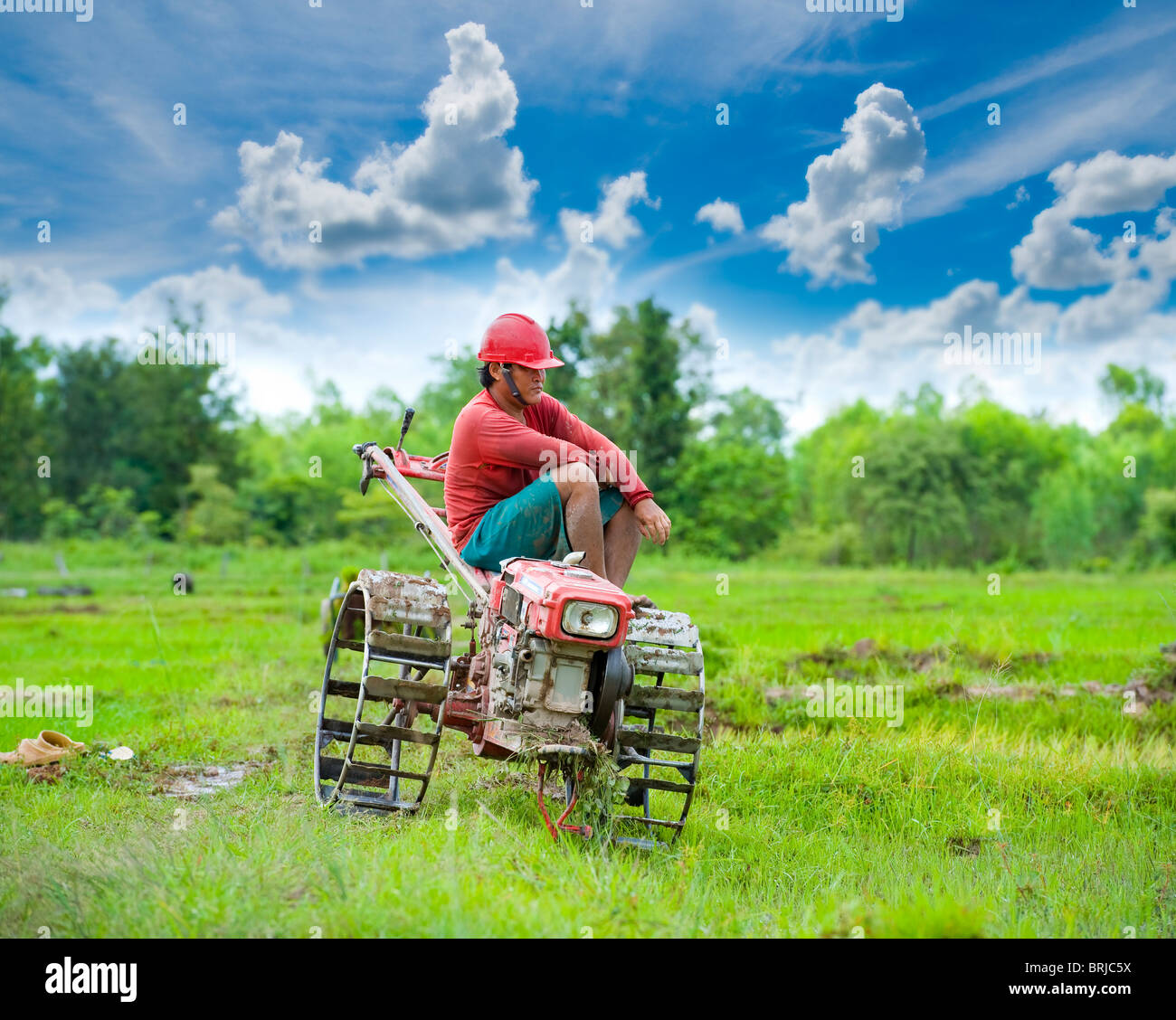 plow man in the rice fields taking a break sitting on his vehicle Stock