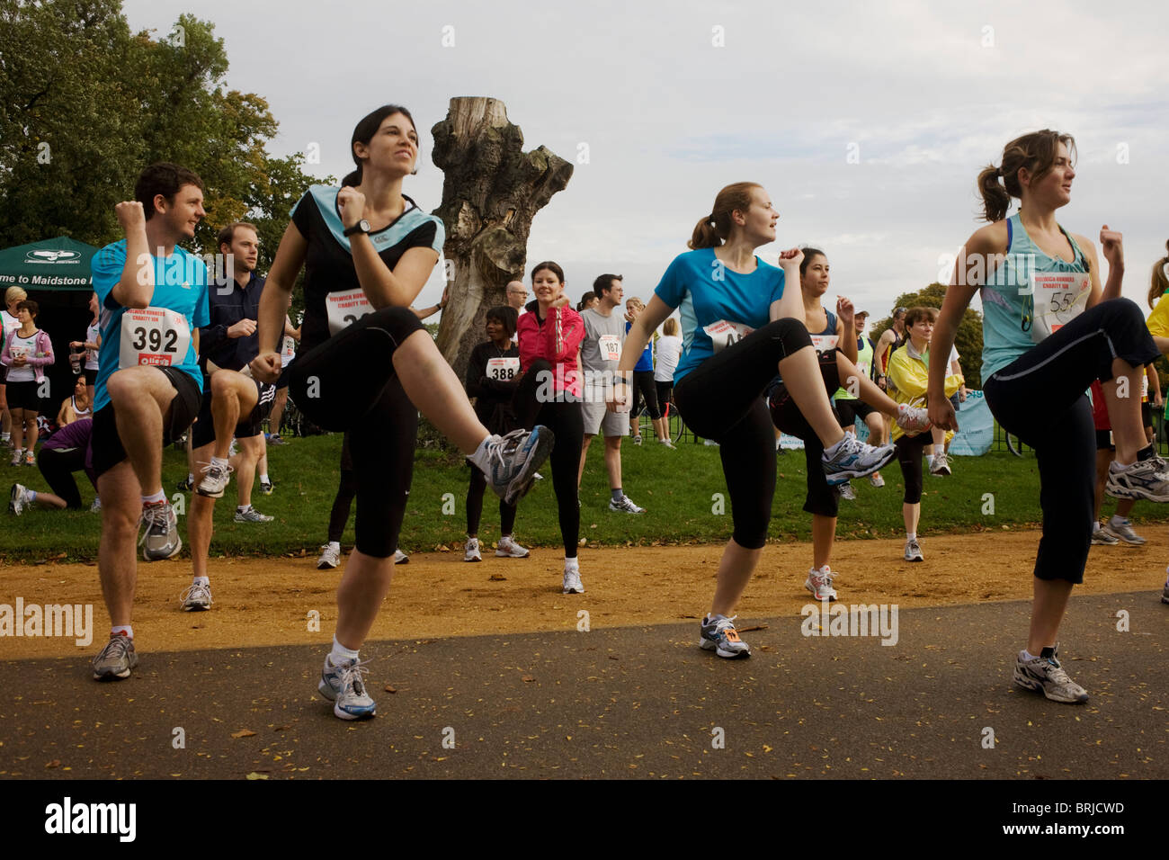 Amateur running club athletes warm-up with group aerobics before a 10k ...