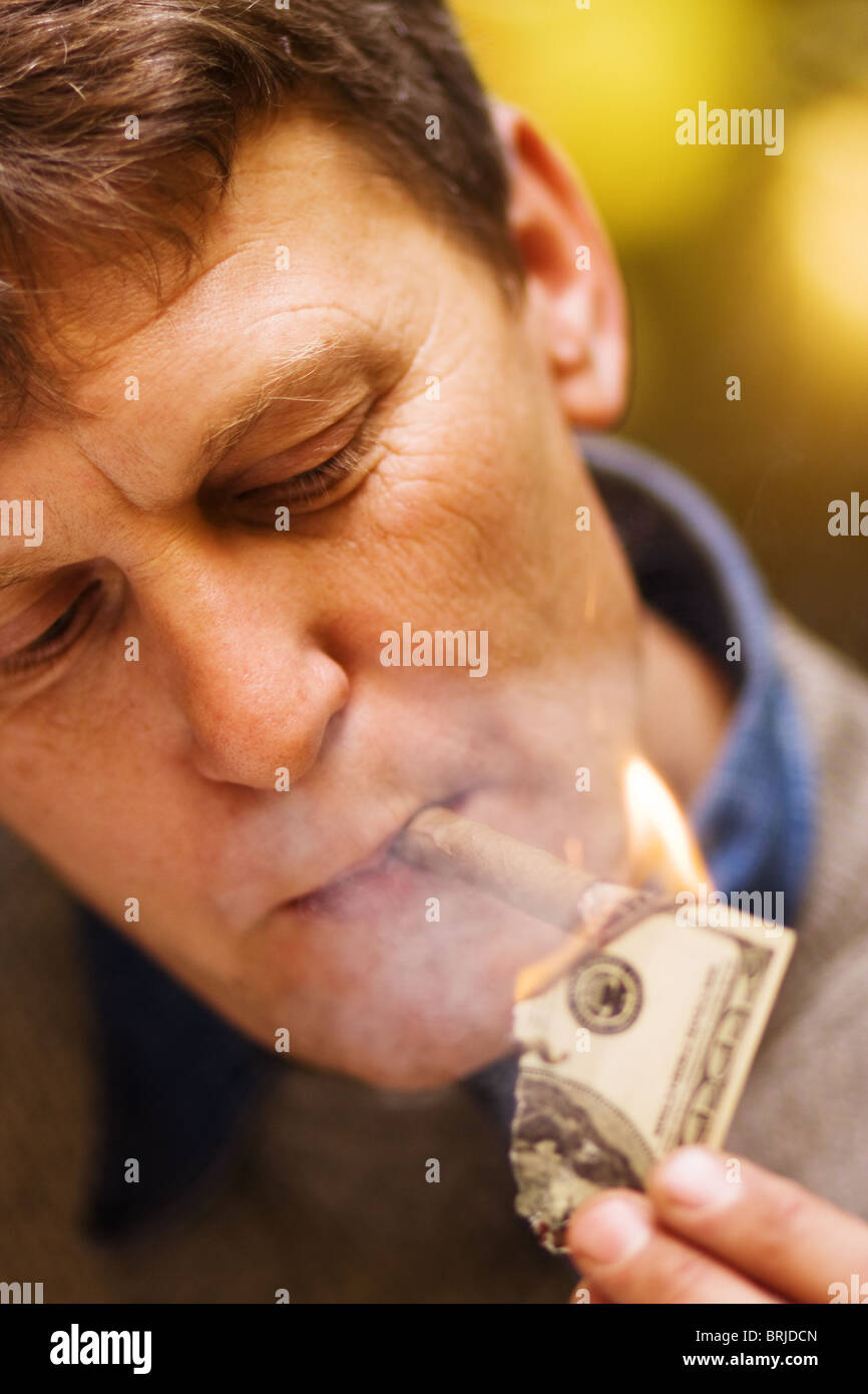 Economy crisis and devaluation of dollar man lighting his cigar with