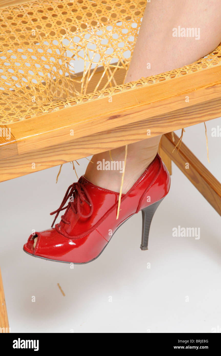 Woman's leg standing on a broken chair with her leg through the broken