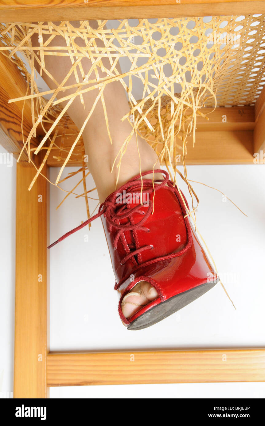 Woman's leg standing on a broken chair with her leg through the broken