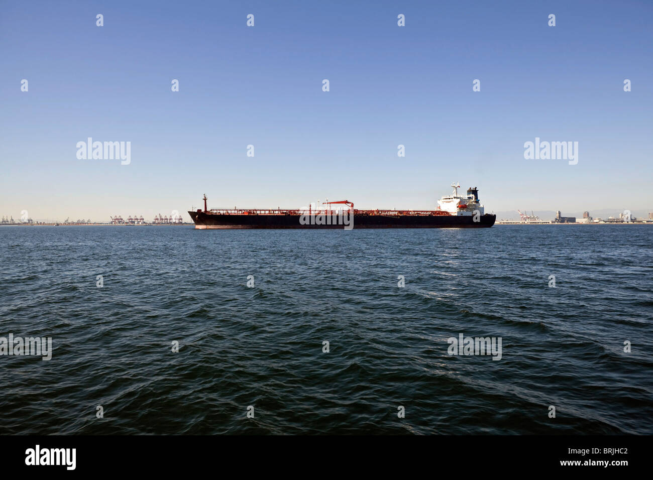 Large oil tanker anchored in a wide industrial harbor. Stock Photo
