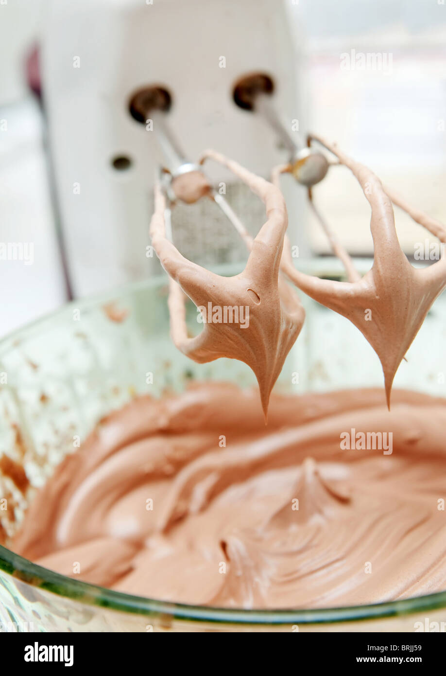 cake mix with white blender dripping batter into the bowl Stock Photo