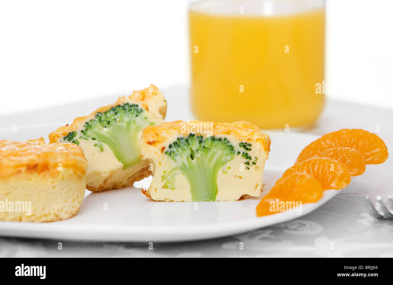 two broccoli cheddar frittata muffins with oranges and orange juice on